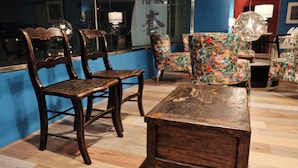 Une table en bois et deux chaises se trouvent dans une pièce dont un mur est bleu et dont le sol est recouvert de planches de bois.