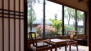 A traditional Japanese room with tatami flooring, a low table, and four wooden chairs.