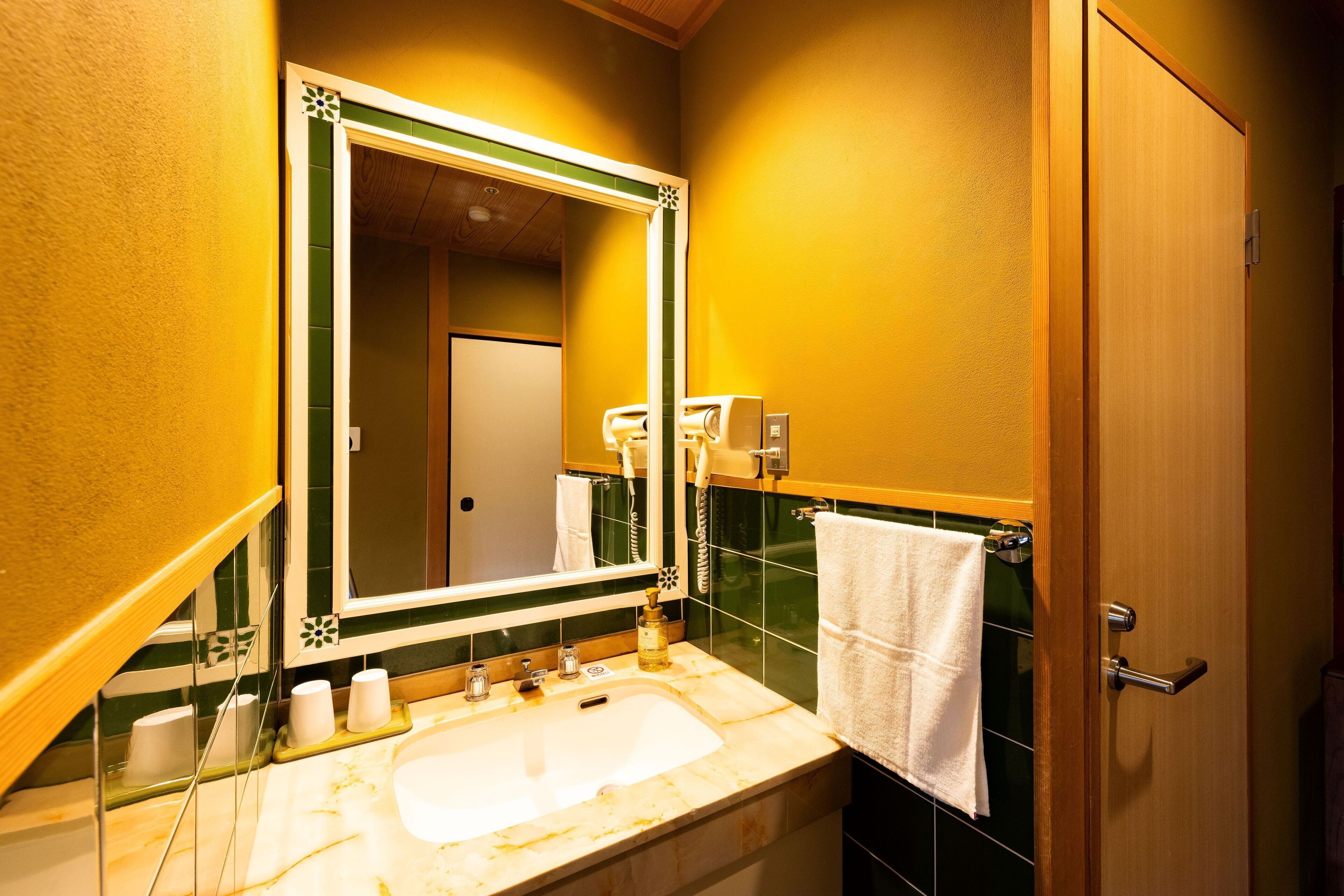 A bathroom with a sink, mirror, towel rack, and a door.
