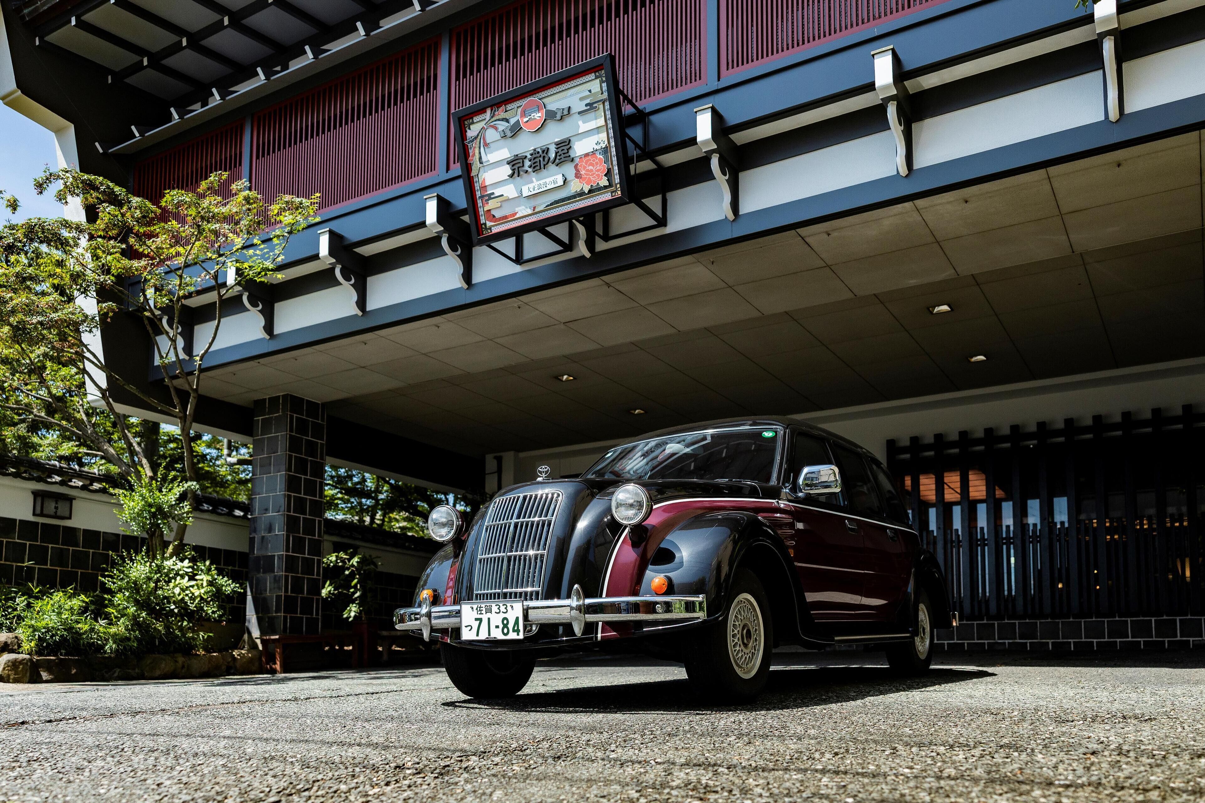 Un coche antiguo estacionado frente a un edificio con detalles arquitectónicos tradicionales y un cartel.