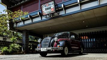 Un coche antiguo estacionado frente a un edificio con detalles arquitectónicos tradicionales y un cartel.