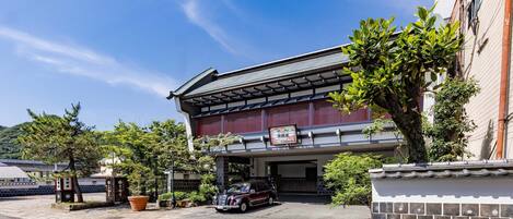 A traditional Japanese building with a covered entrance and a parked car in front.