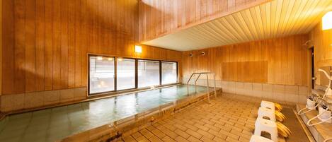 A wooden interior with a pool, benches, and a sauna area.