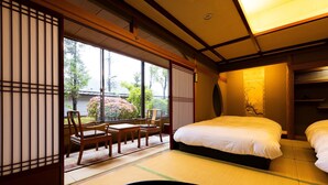 A traditional Japanese-style room with tatami flooring, a bed, a desk, and chairs.