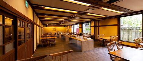 A restaurant with wooden furniture, a long counter, and large windows.
