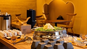 A buffet setup with a large silver platter, various bowls, and utensils on a wooden table.
