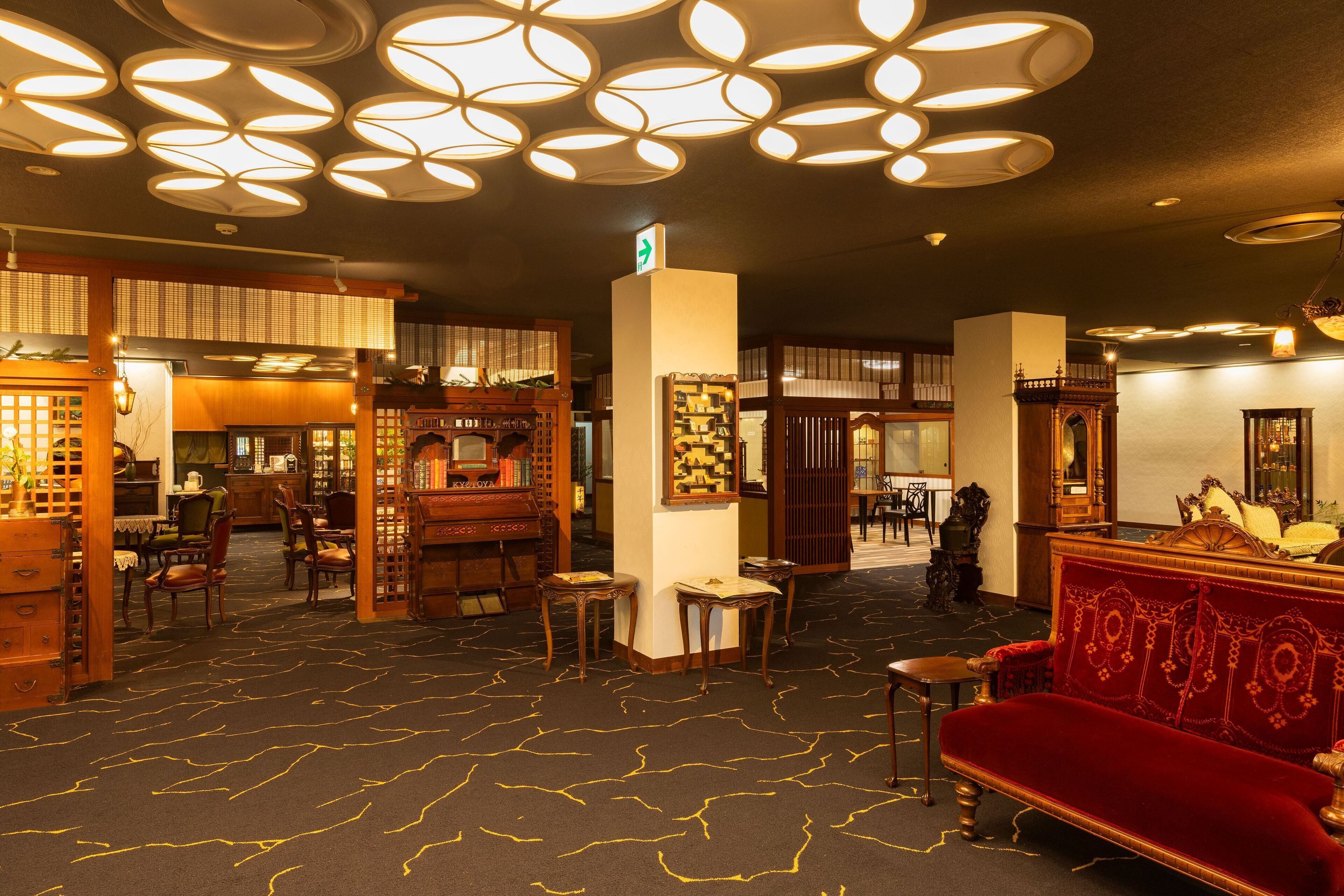A hotel lobby with a patterned carpet, wooden furniture, and a red sofa.