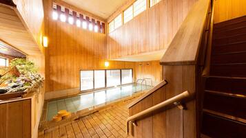 A wooden interior with a pool, wooden stairs, and a railing.