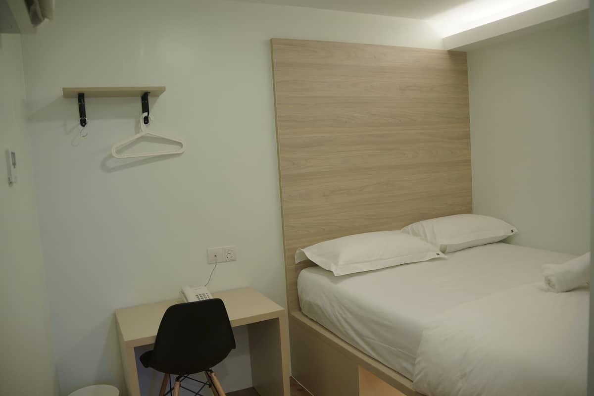 Um quarto com uma cama, uma escrivaninha e uma cadeira.