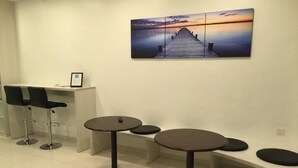 A modern interior with a desk, two bar stools, and three round tables with stools. - Hotel 57 Subang Jaya (Subang Jaya)