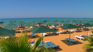 Pantai pribadi, kursi berjemur, payung pantai, dan handuk pantai