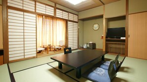 Um quarto japonês tradicional com tatames, uma mesa baixa e portas deslizantes.