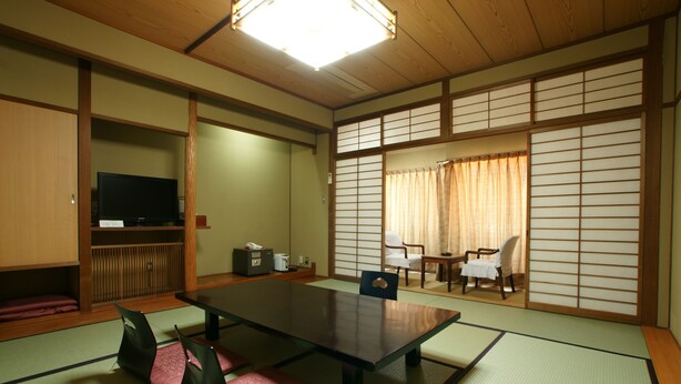 Um quarto japonês tradicional com tatames, uma mesa baixa e portas deslizantes.