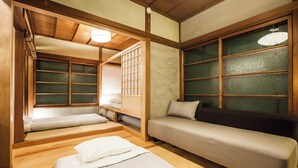 Una habitación tradicional japonesa con suelo de tatami, futón, cama baja de madera y puertas correderas shoji.