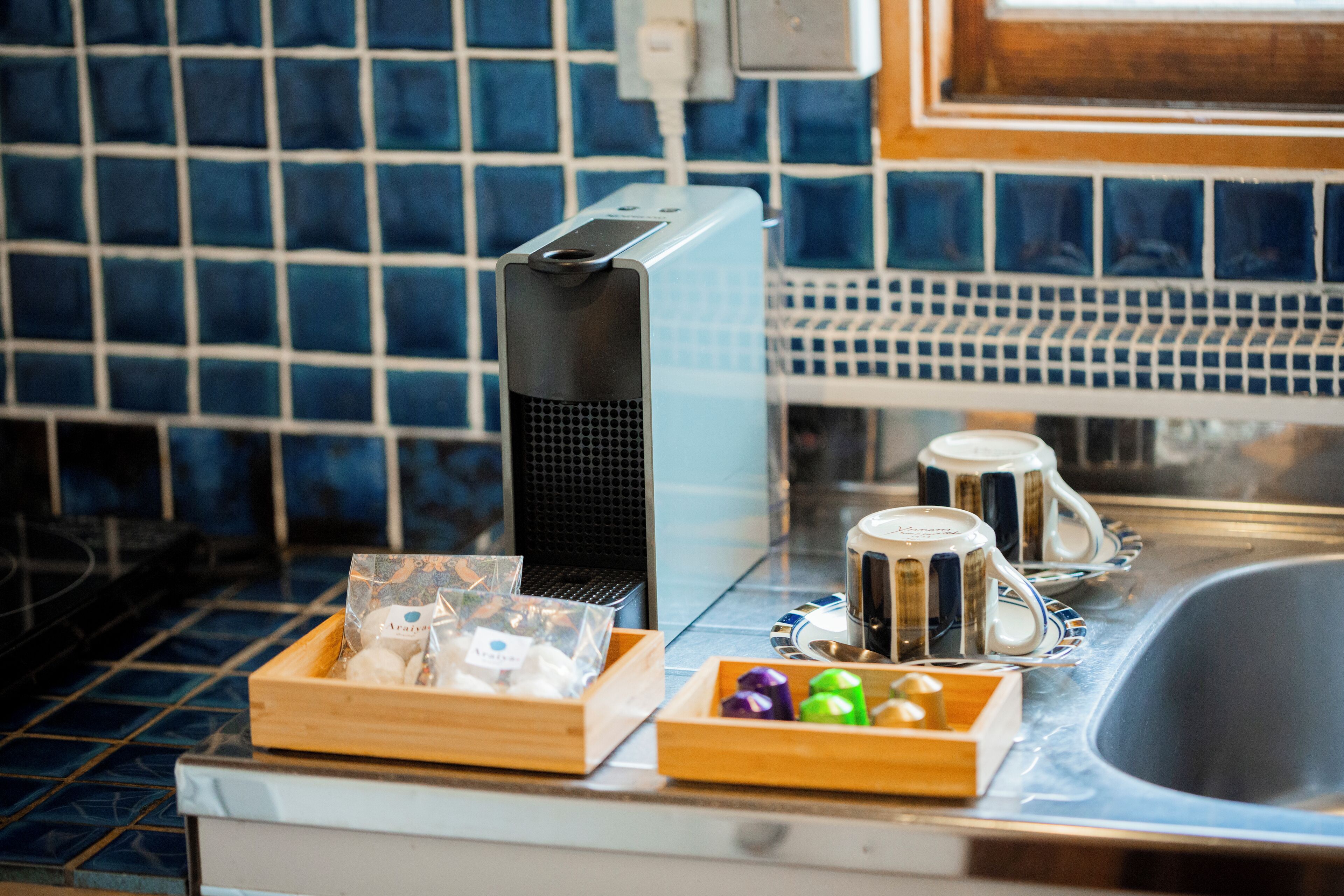 A kitchen counter with a coffee maker, a box of tea bags, and a tray of colorful candies.