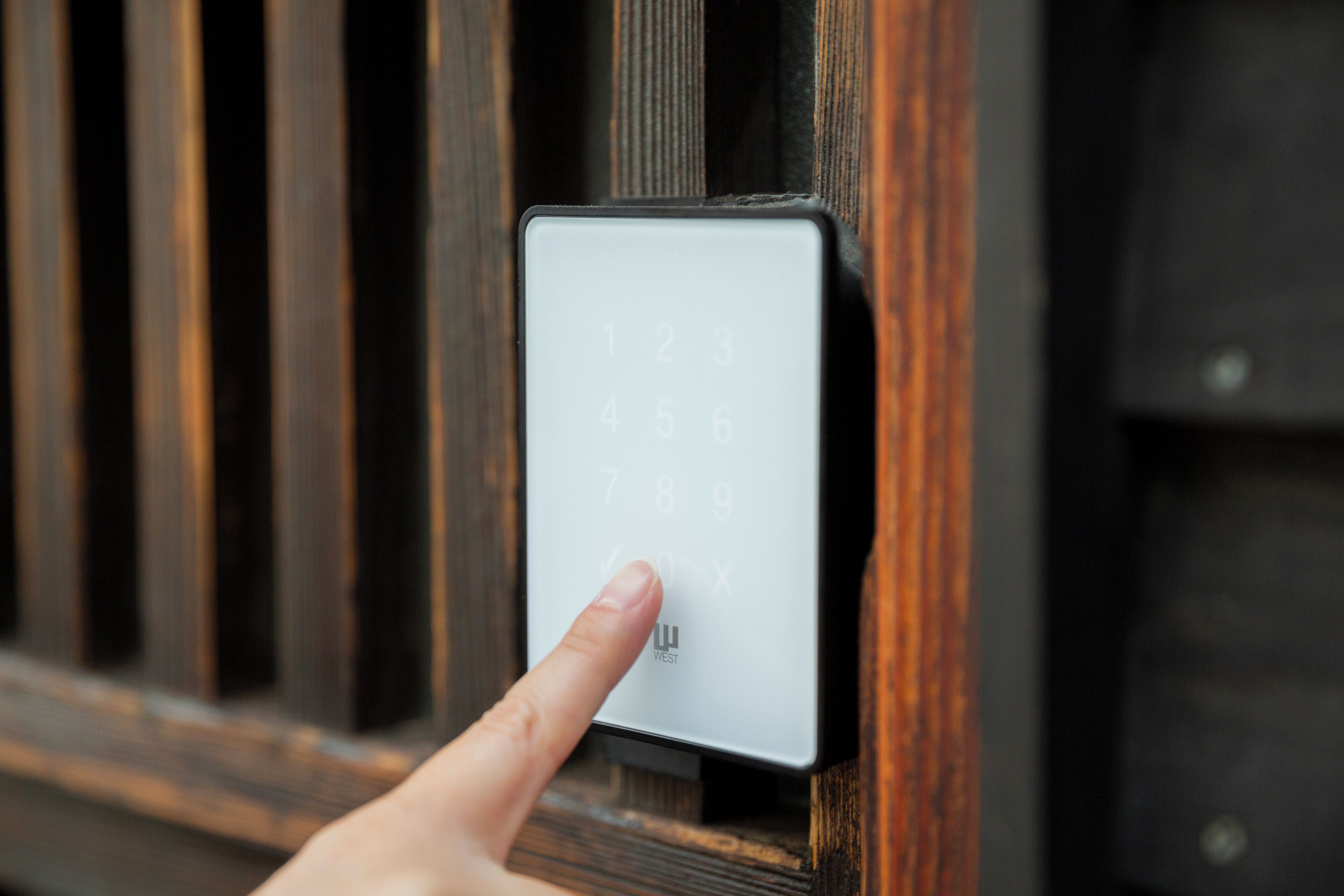 Een hand drukt op een numeriek keypad op een deur.