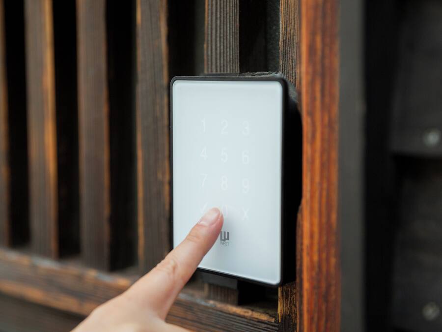 Een hand drukt op een numeriek keypad op een deur.
