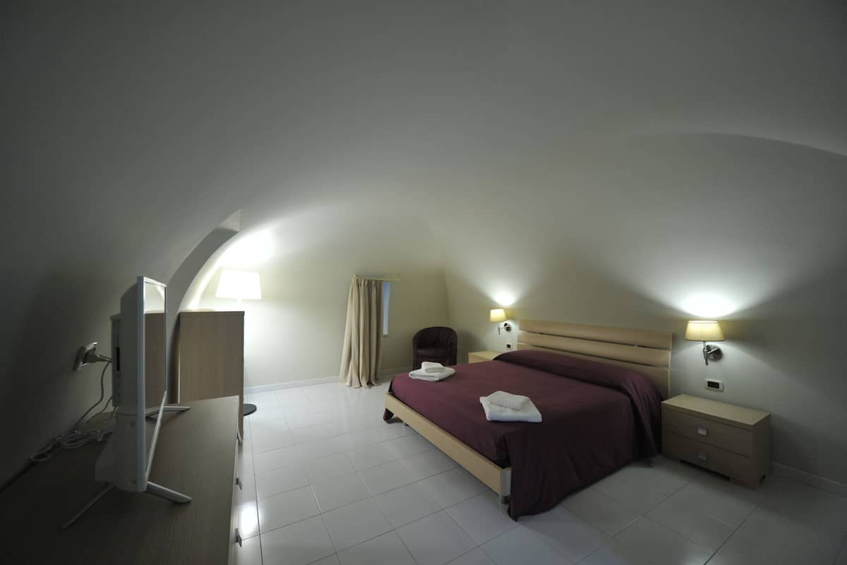 A bedroom with a bed, bedside tables, a lamp, and a TV.