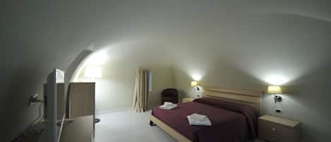 A bedroom with a bed, bedside tables, a lamp, and a TV.