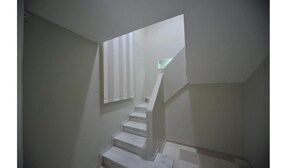A staircase with a unique geometric design, leading to a landing with a small window.