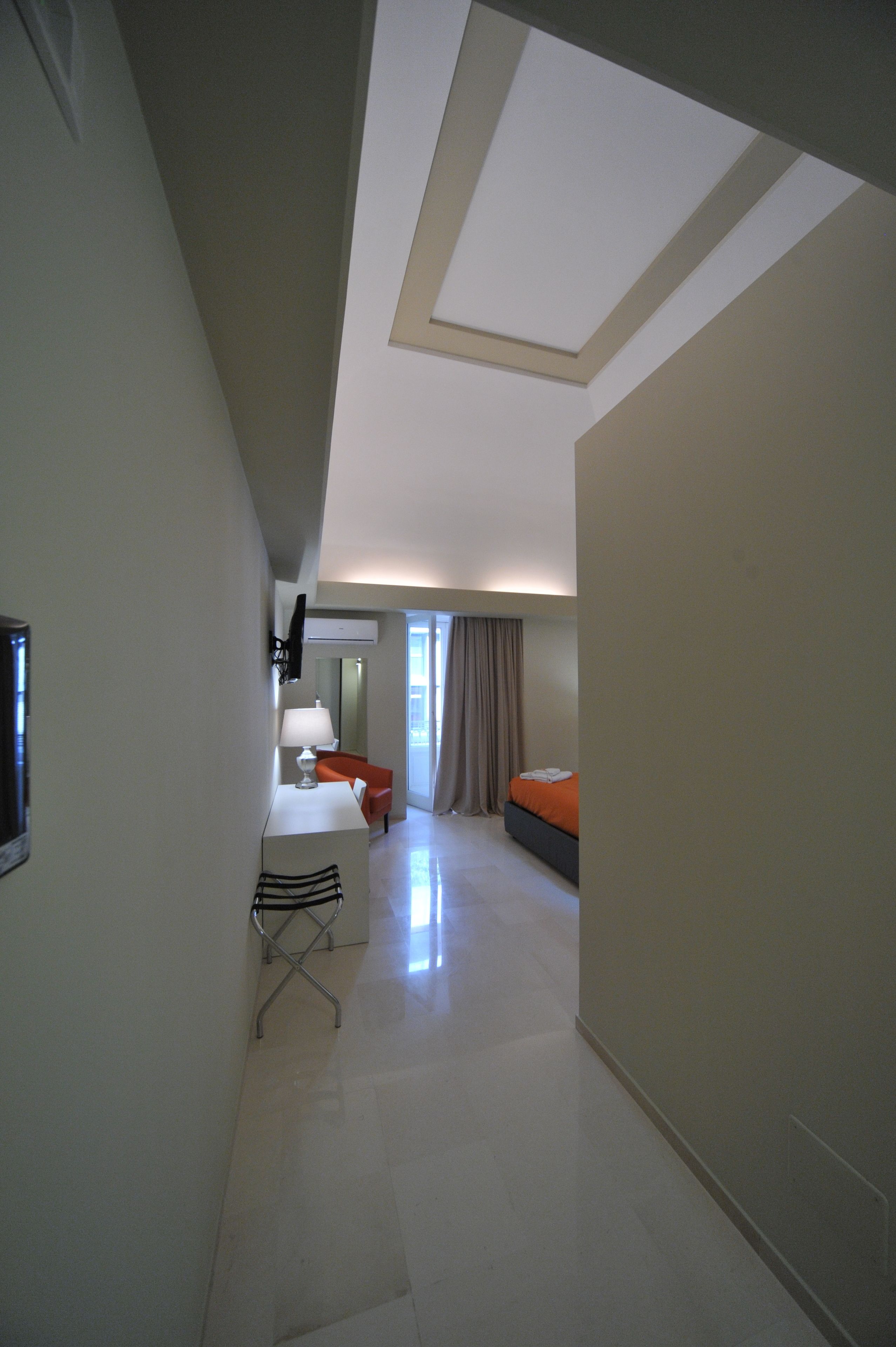 A hotel room with a desk, chair, bed, and a large window.