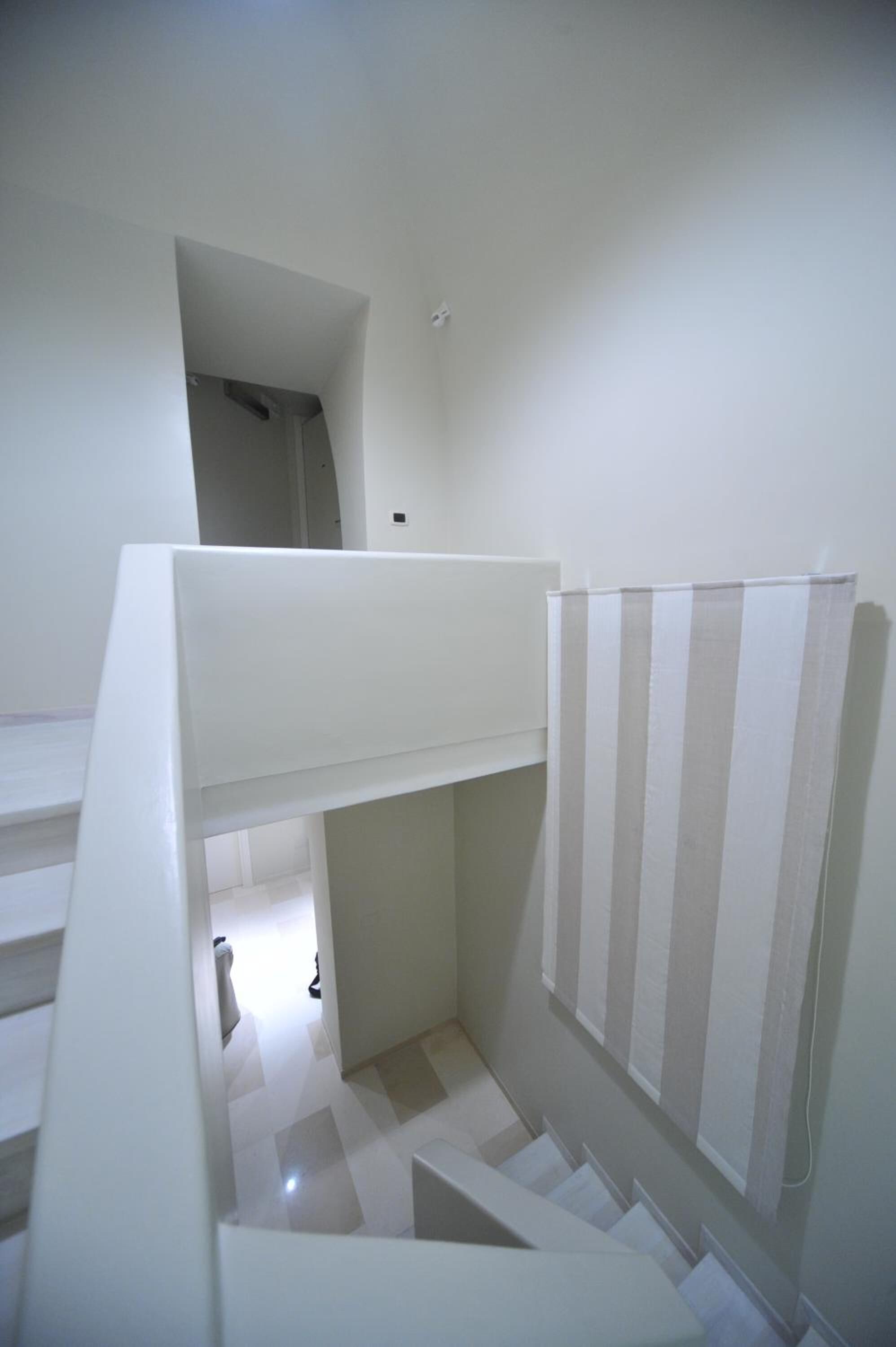 A staircase with a white handrail and striped curtains.