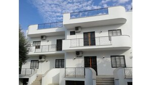 A multi-story white building with balconies and windows.