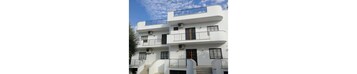 A multi-story white building with balconies and windows.