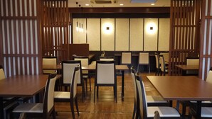 Un restaurant avec des tables et des chaises en bois, un sol carrelé et des cloisons de style japonais traditionnel.