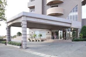 A modern building with a covered entrance labeled "BUSINESS INN". - Business Inn Umesaki (Nagasu)