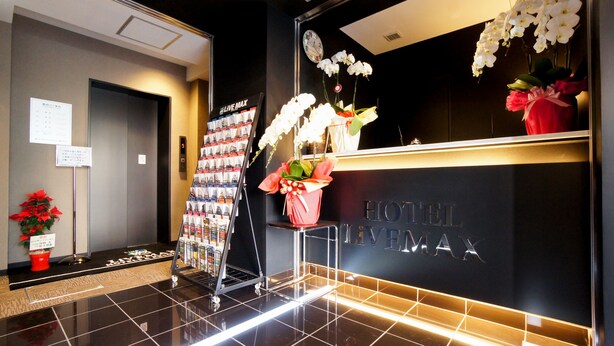 A hotel reception area with a modern design, featuring a reception desk, a clock, and a display of magazines.