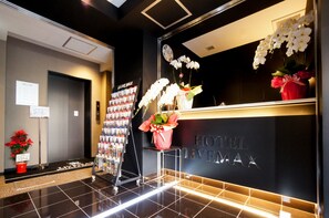 A hotel reception area with a modern design, featuring a reception desk, a clock, and a display of magazines. - Hotel LiVEMAX Umeda Nakatsu (Osaka)