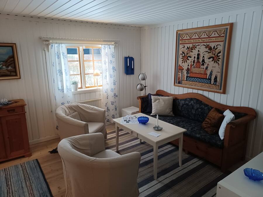 A cozy living room with a sofa, armchairs, a coffee table, and a painting on the wall.