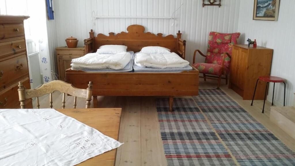 A bedroom with a wooden bed, a wooden dresser, a chair, and a small table.