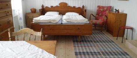 A bedroom with a wooden bed, a wooden dresser, a chair, and a small table.
