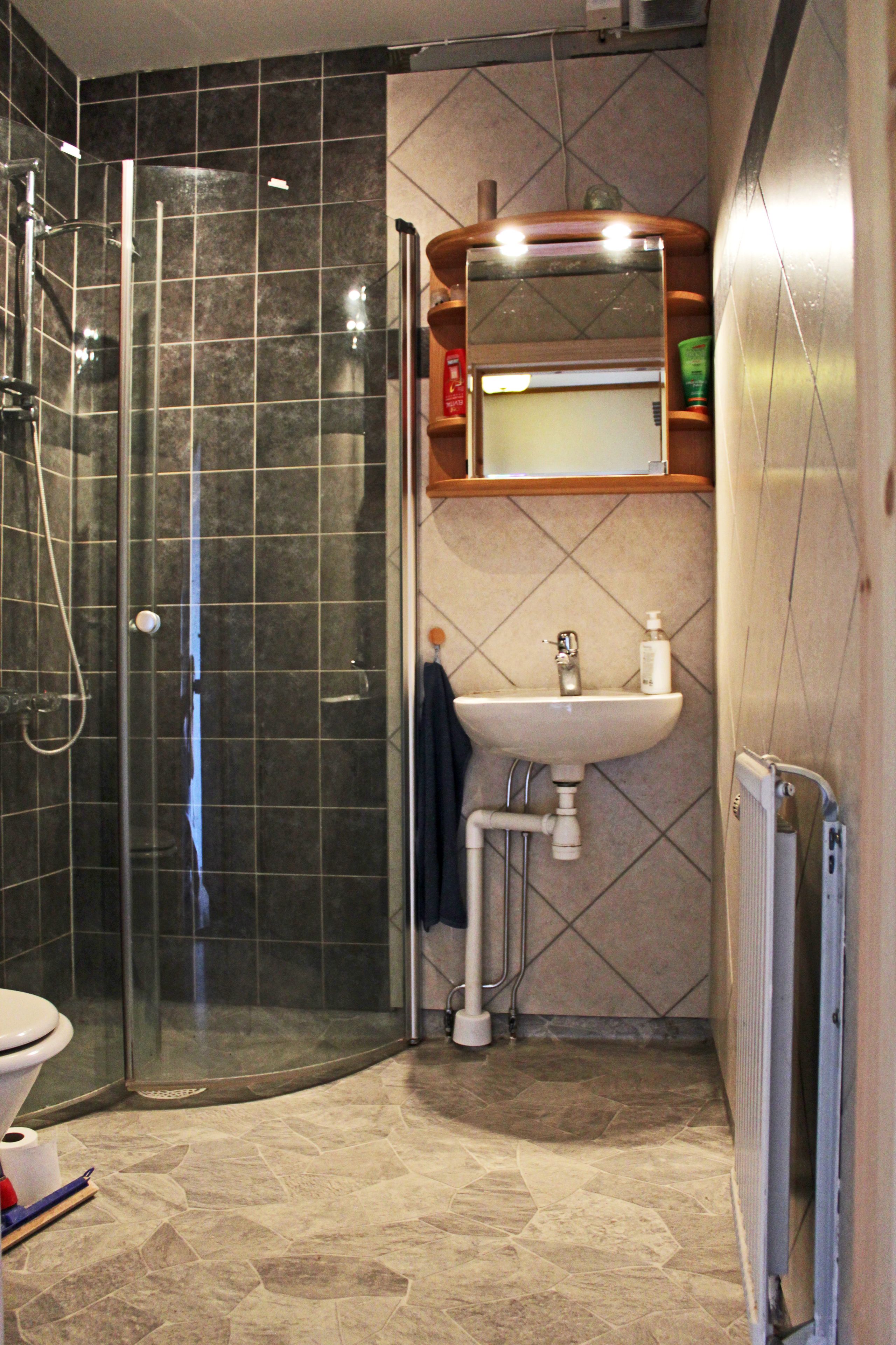 A bathroom with a glass-enclosed shower, a sink with a mirror above it, and a towel hanging on the wall.