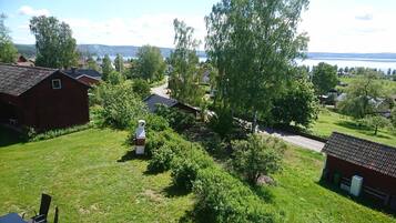 En lantlig miljö med hus, en väg och en vattenyta i bakgrunden.