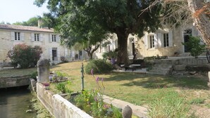 A stone building with a courtyard, a small pond, and a tree. - Jolysable (Pons)