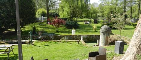 A garden with a fountain, seating area, and a stone structure.