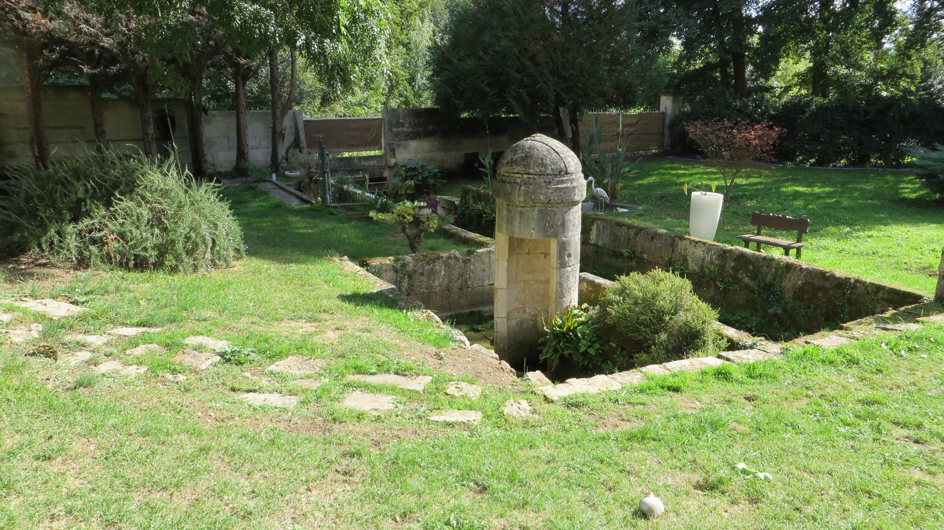 A garden with a stone structure, a bench, and a pathway.