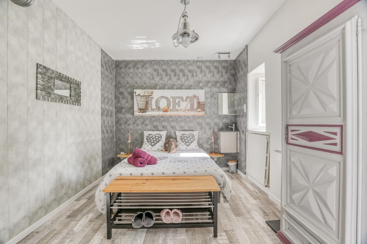 A bedroom with a bed, a bench, a mirror, and a wardrobe.