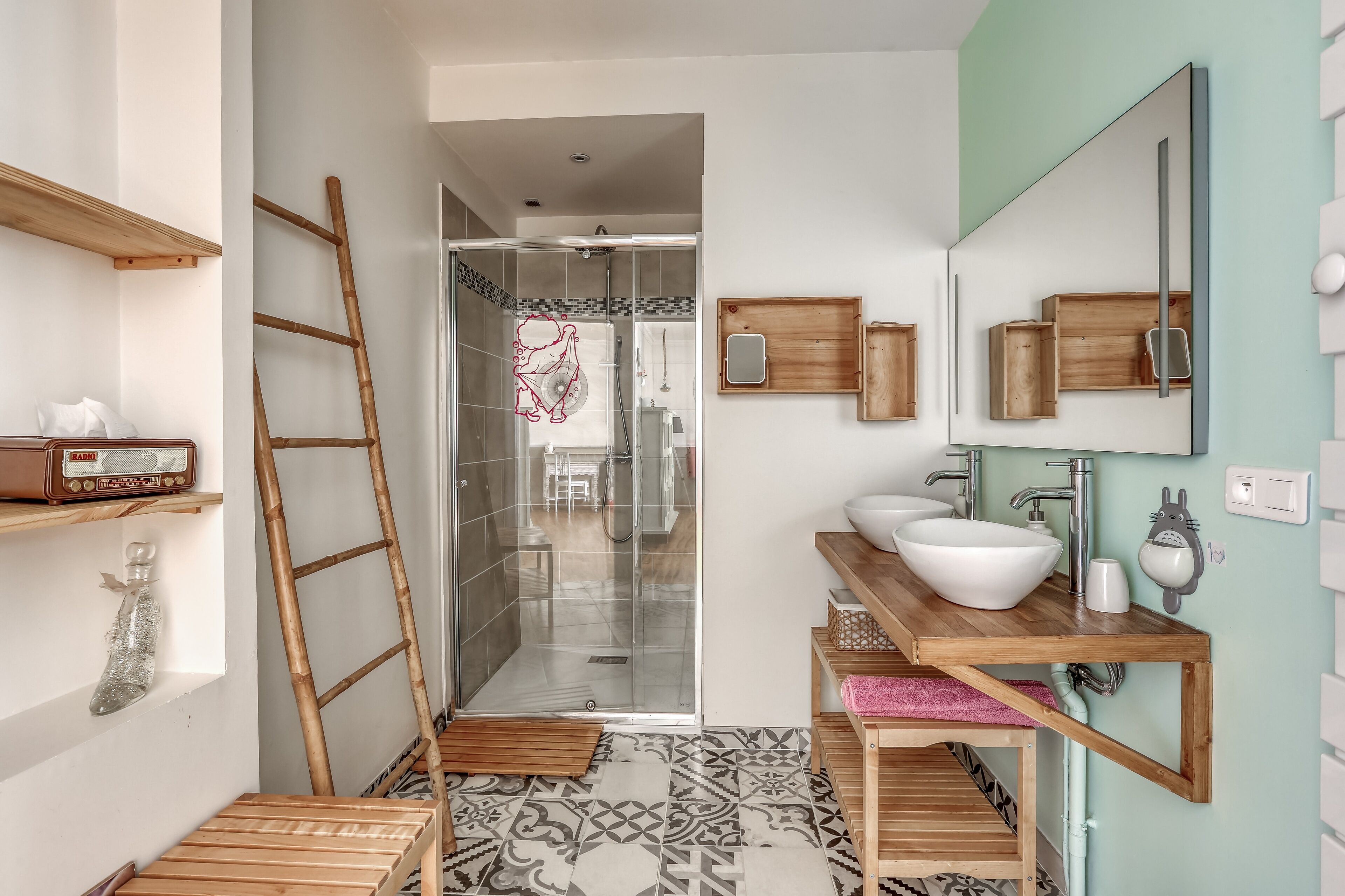 A bathroom with a wooden vanity, a large mirror, and a shower area.