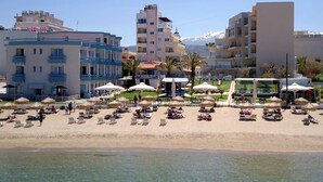 Un hôtel situé en bord de mer, doté de nombreux balcons, de chaises longues et de parasols.