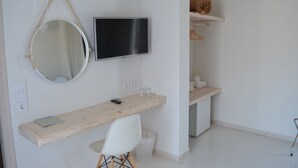 Une chambre moderne et minimaliste, dotée d’un bureau en bois, d’un miroir rond, d’un téléviseur à écran plat et d’une chaise blanche.