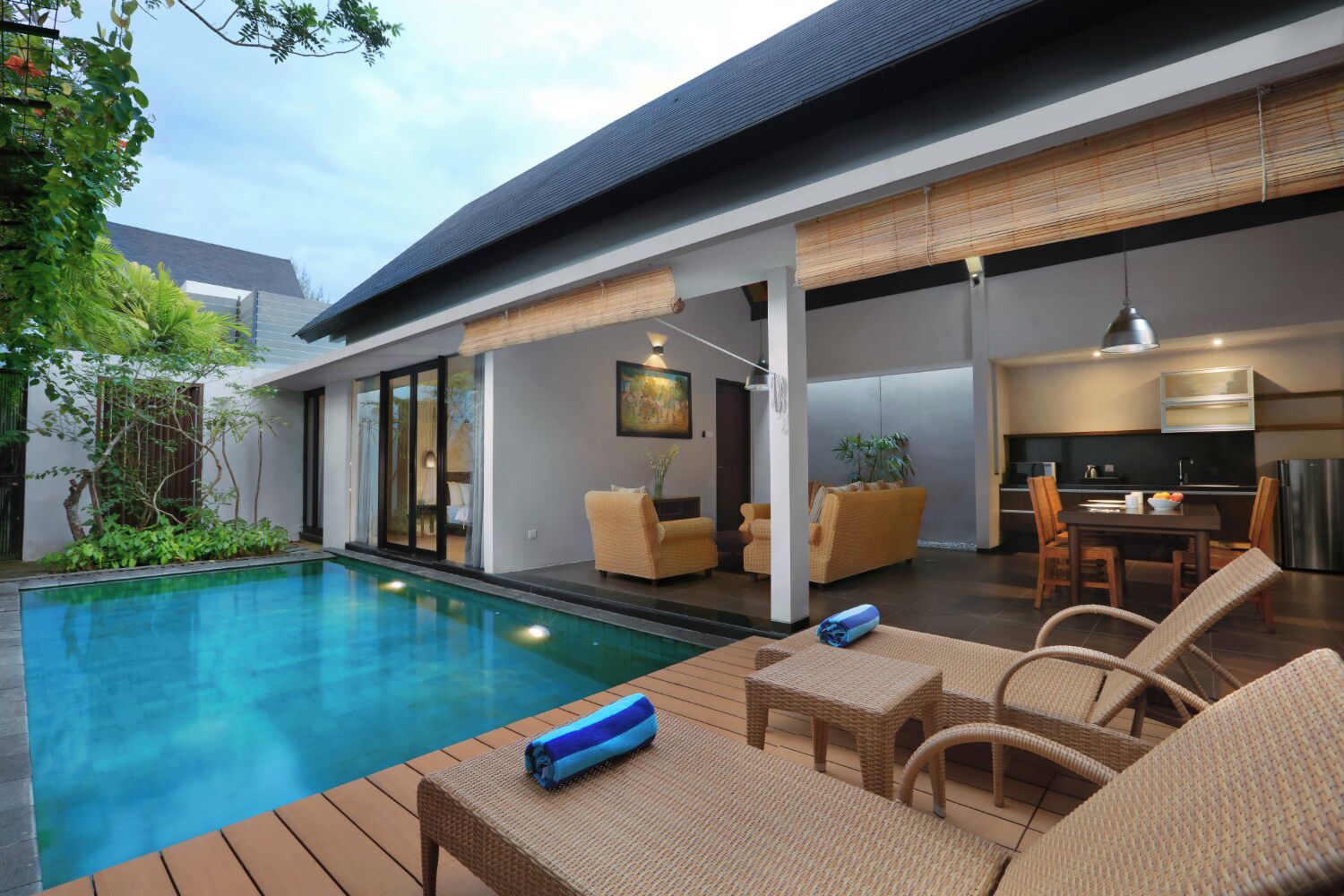 A modern outdoor pool area with lounge chairs and a dining table.