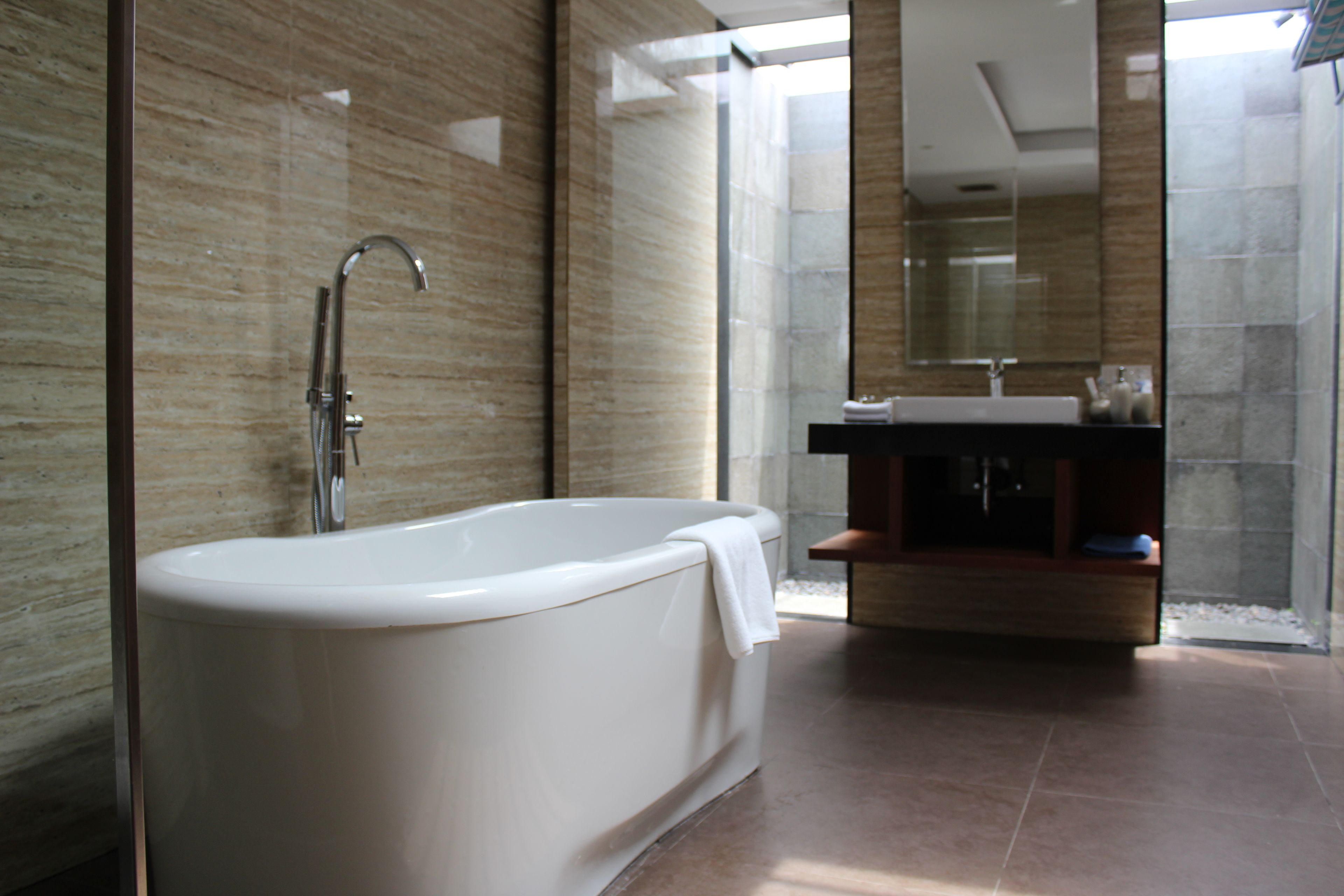 Un baño moderno con una bañera independiente, cabina de ducha de vidrio y tocador con espejo.