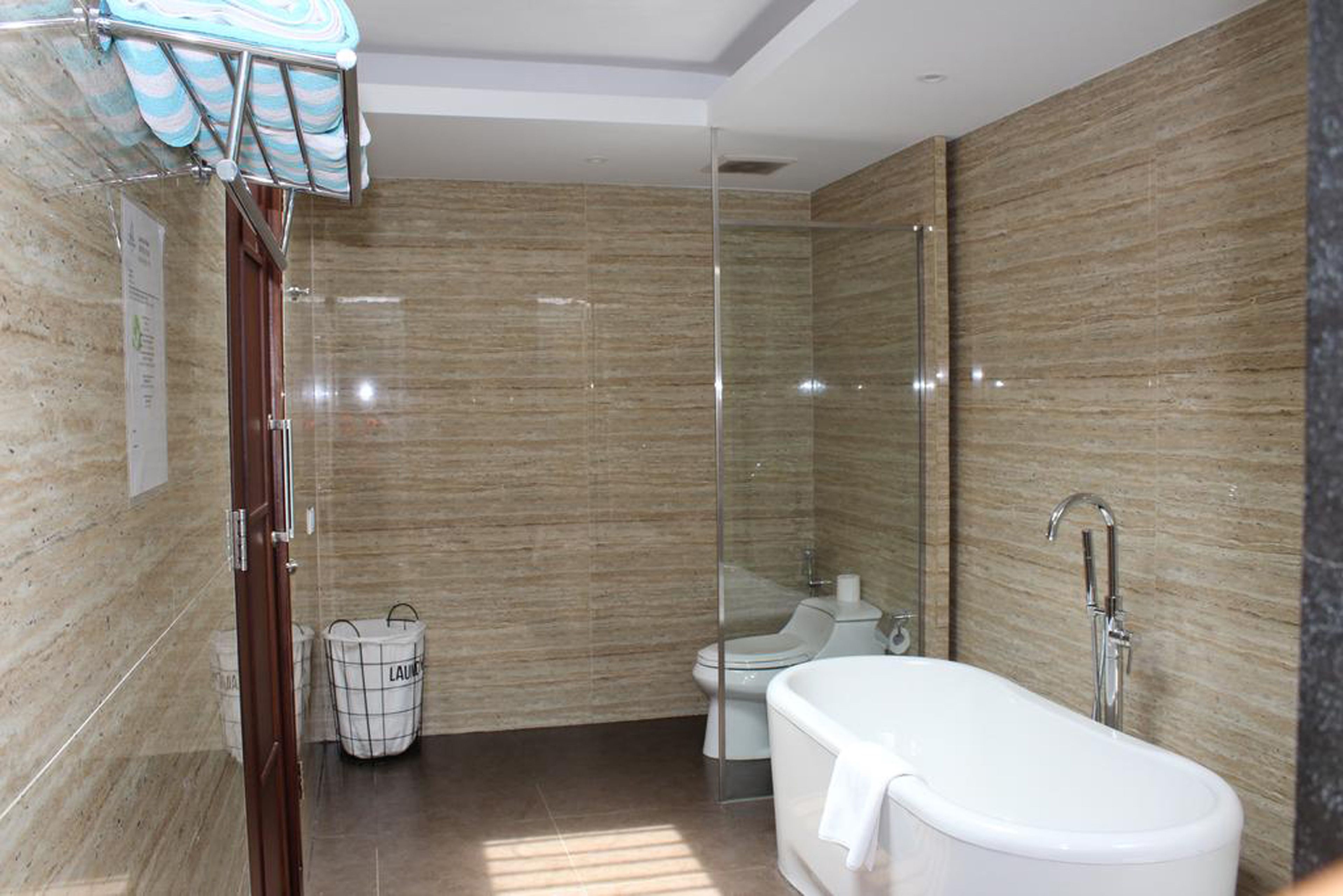 Une salle de bain moderne avec une douche à l’italienne en verre, une baignoire blanche et des toilettes.