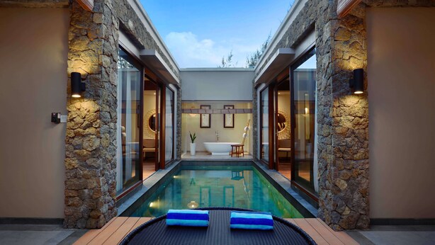 A pool area with stone walls, a bathtub, and a lounge chair. - Kamuela Villas Lagoi Bay Bintan (Bintan)