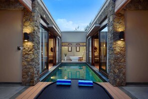 A pool area with stone walls, a bathtub, and a lounge chair. - Kamuela Villas Lagoi Bay Bintan (Bintan)