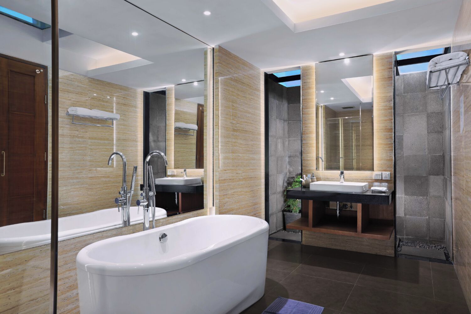 Un baño moderno con una bañera independiente, dos lavamanos y un espejo grande.